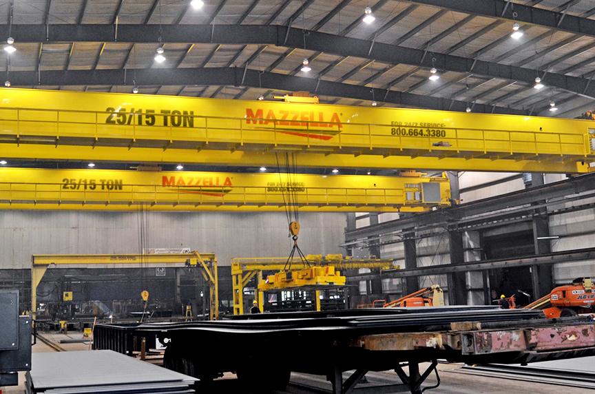 Yellow 25/15-ton overhead bridge crane system in industrial facility with worker operating hoist below