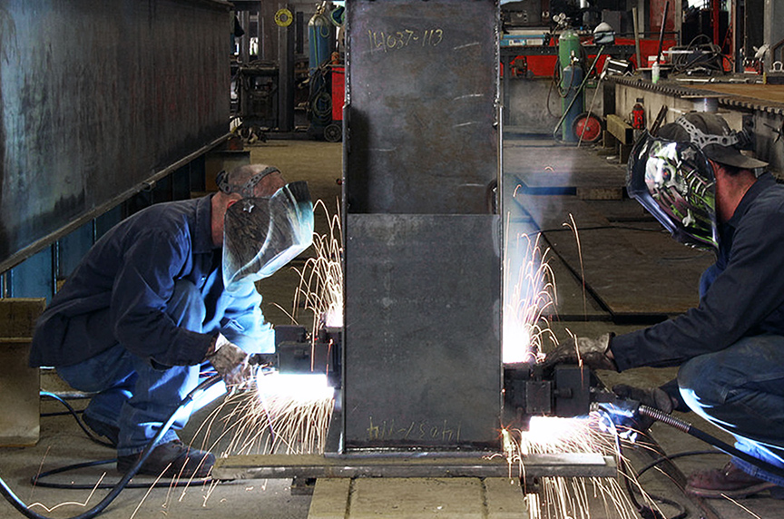 Two welders fabricating an overhead crane box girder in a manufacturing facility
