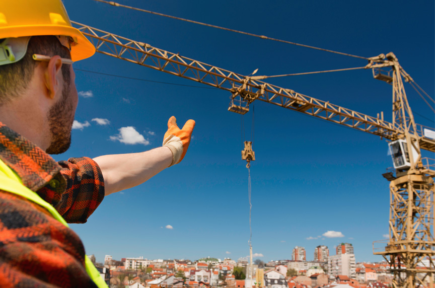 Tower crane operator responds during a lift to signals from a worker on the ground