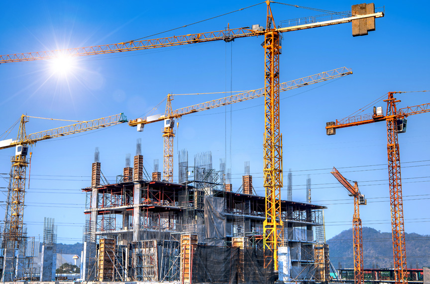 Multiple Tower Cranes on Construction Site with Electrified Power Lines Around Perimeter