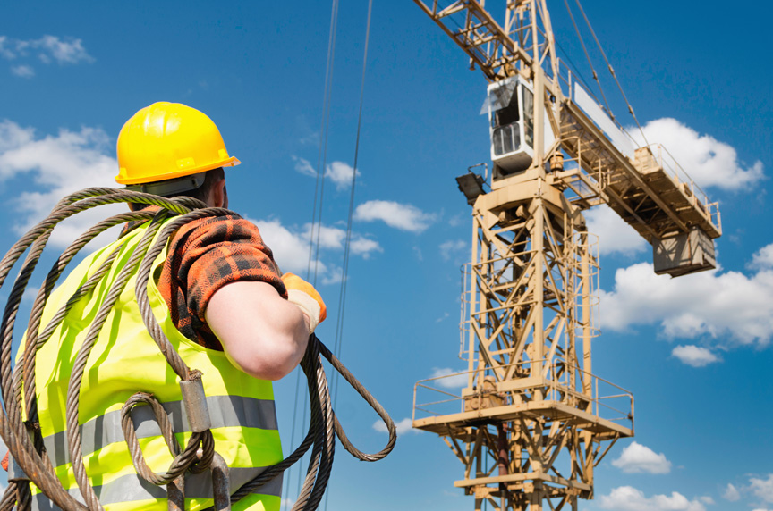 Rigger with wire rope sling preparing to rig a load for tower crane