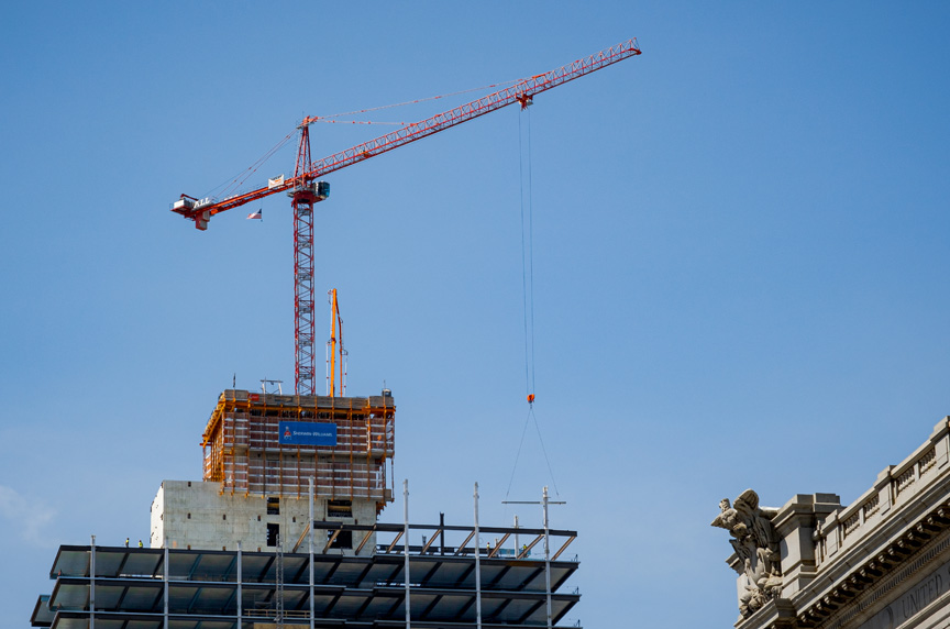 Tower crane in city making a lift on a new construction building site