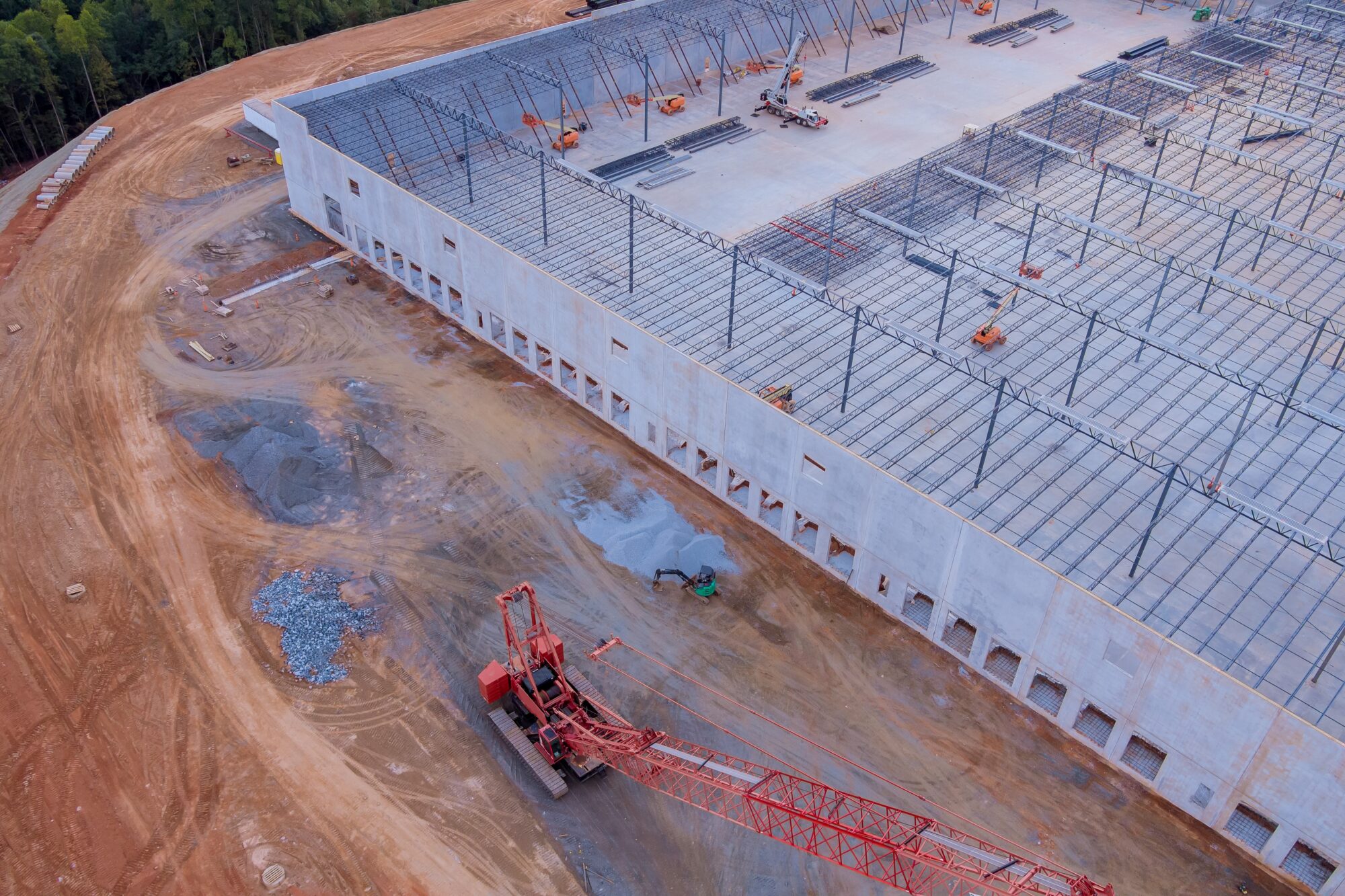An aerial view of a data center under construction with a large red crawler crane outside.