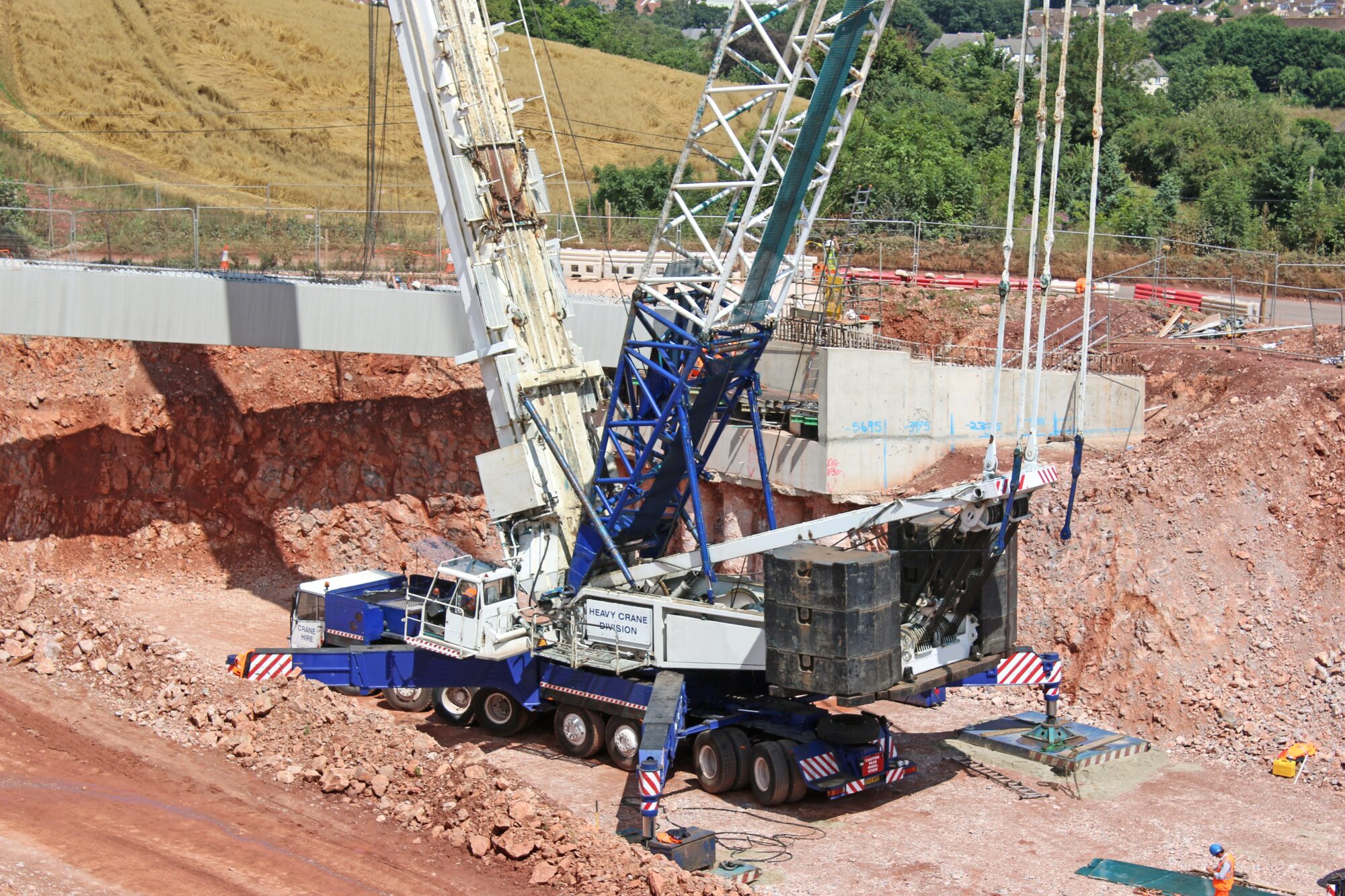 A rough terrain crane being operated on a construction site on a sunny day.